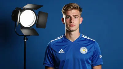 A photorealistic image of an anonymous 19-year-old Finnish centre-back in a Leicester City kit, standing at 6ft 6in, with...