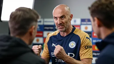 A 35-year-old, ruggedly-built, balding assistant coach of Leicester City, dressed in the club's home kit of blue shirt...