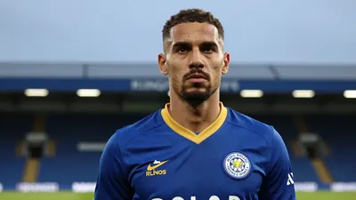 A close-up shot of a rugged, 35-year-old, experienced centre-back in Leicester City's iconic blue and amber home kit, the...